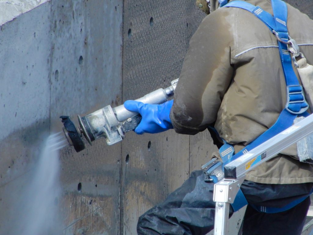 コンクリートの壁を高圧洗浄で洗浄する様子を写した画像